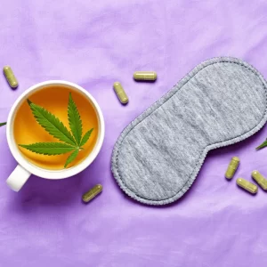 a cup of tea with a leaf in it next to a mask and pills cannabis for sleep