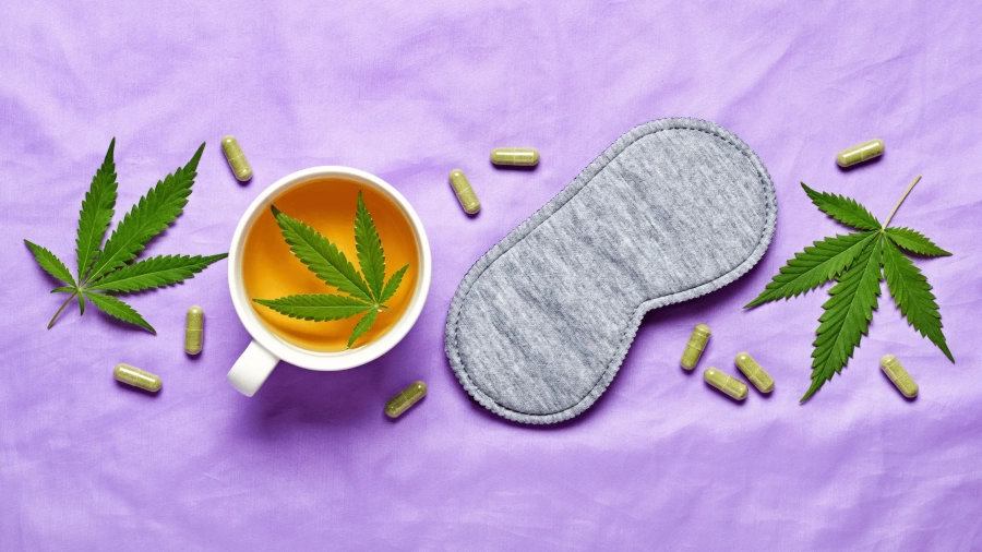 a cup of tea with a leaf in it next to a mask and pills cannabis for sleep