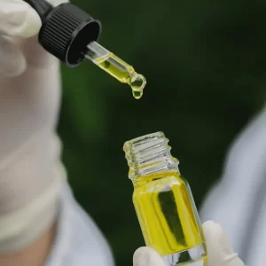 a person holding a dropper over a small bottle of liquid